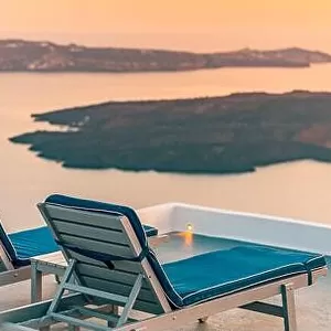 Infinity pool on the rooftop at sunset in Santorini Island, Greece. Beautiful poolside and sunset sky. Luxurious summer vacation and holiday concept